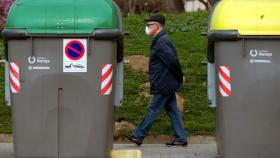 Un hombre con una mascarilla pasea por el centro de Barcelona junto a unos contenedores.