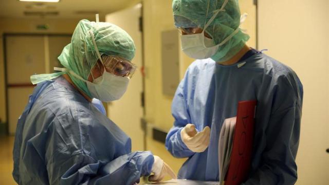 Dos médicos conversan completamente protegidos.