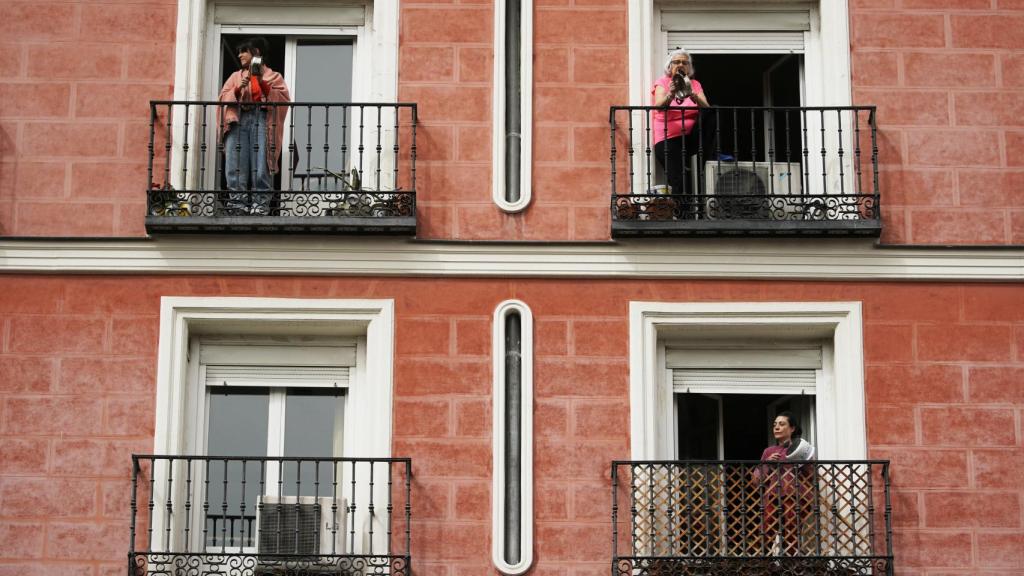 Varias mujeres, con sus cacerolas, en los balcones de sus casas.