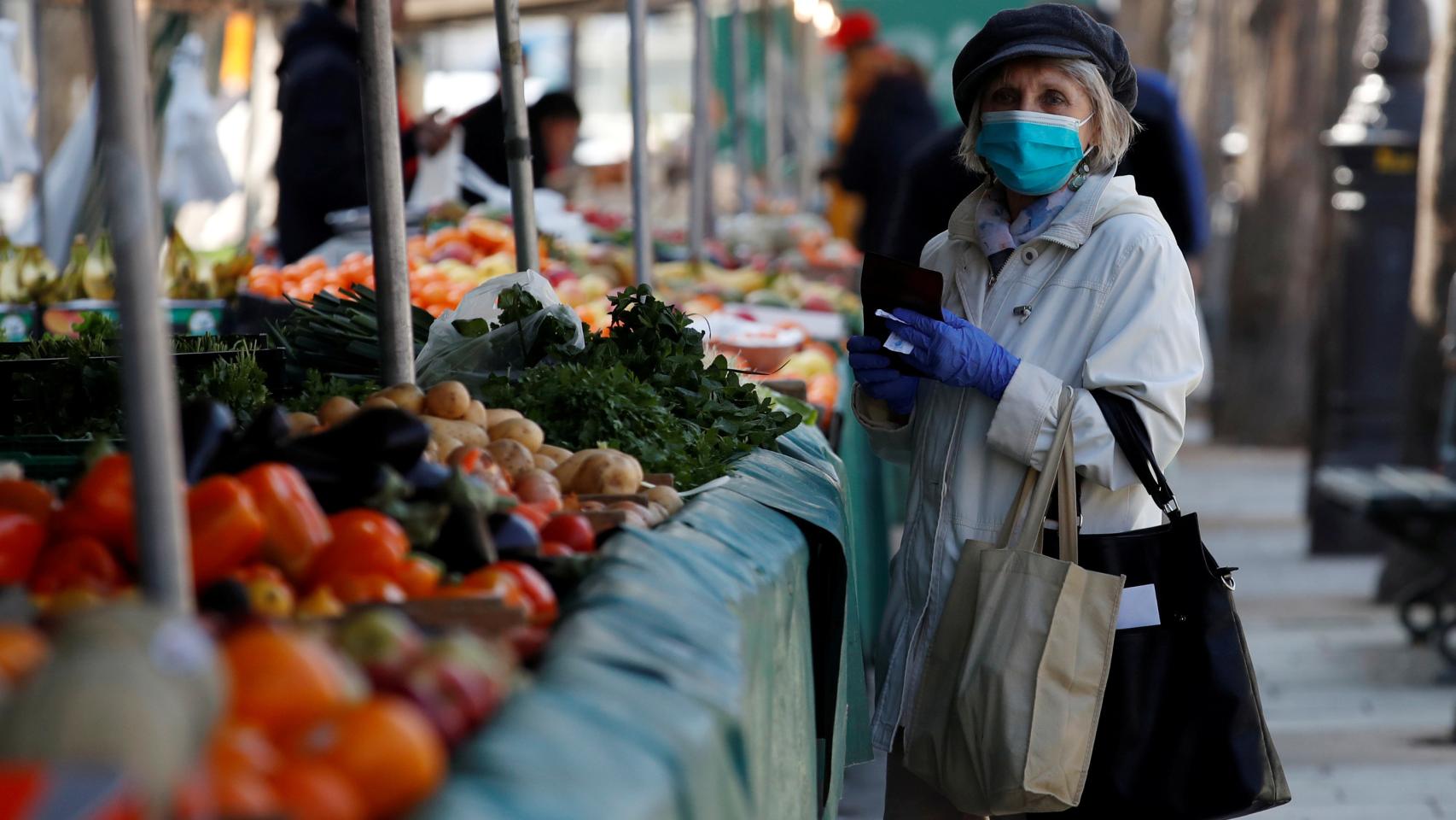 Una mujer en el mercado con mascarilla.