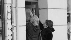 Imagen de archivo de dos mujeres abriendo la persiana de un negocio.