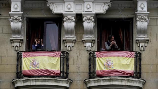 Dos ciudadanos aplauden desde los balcones de sus casas, en Madrid.