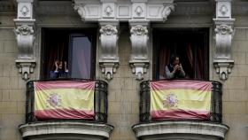 Dos ciudadanos aplauden desde los balcones de sus casas, en Madrid.