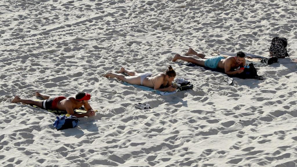 Bañistas toman el sol mientras mantienen la distancia de seguridad en Perth, Australia. EFE/EPA Richard Wainwaight