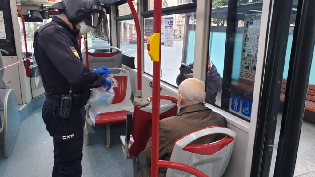 Un policía reparte mascarillas en un bus urbano de A Coruña
