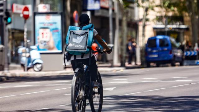 Un 'rider' de la compañía de comida a domicilio, Deliveroo, circula con su bicicleta por una calle de Madrid.