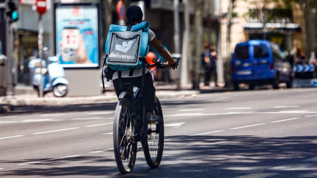 Un 'rider' de la compañía de comida a domicilio, Deliveroo, circula con su bicicleta por una calle de Madrid.
