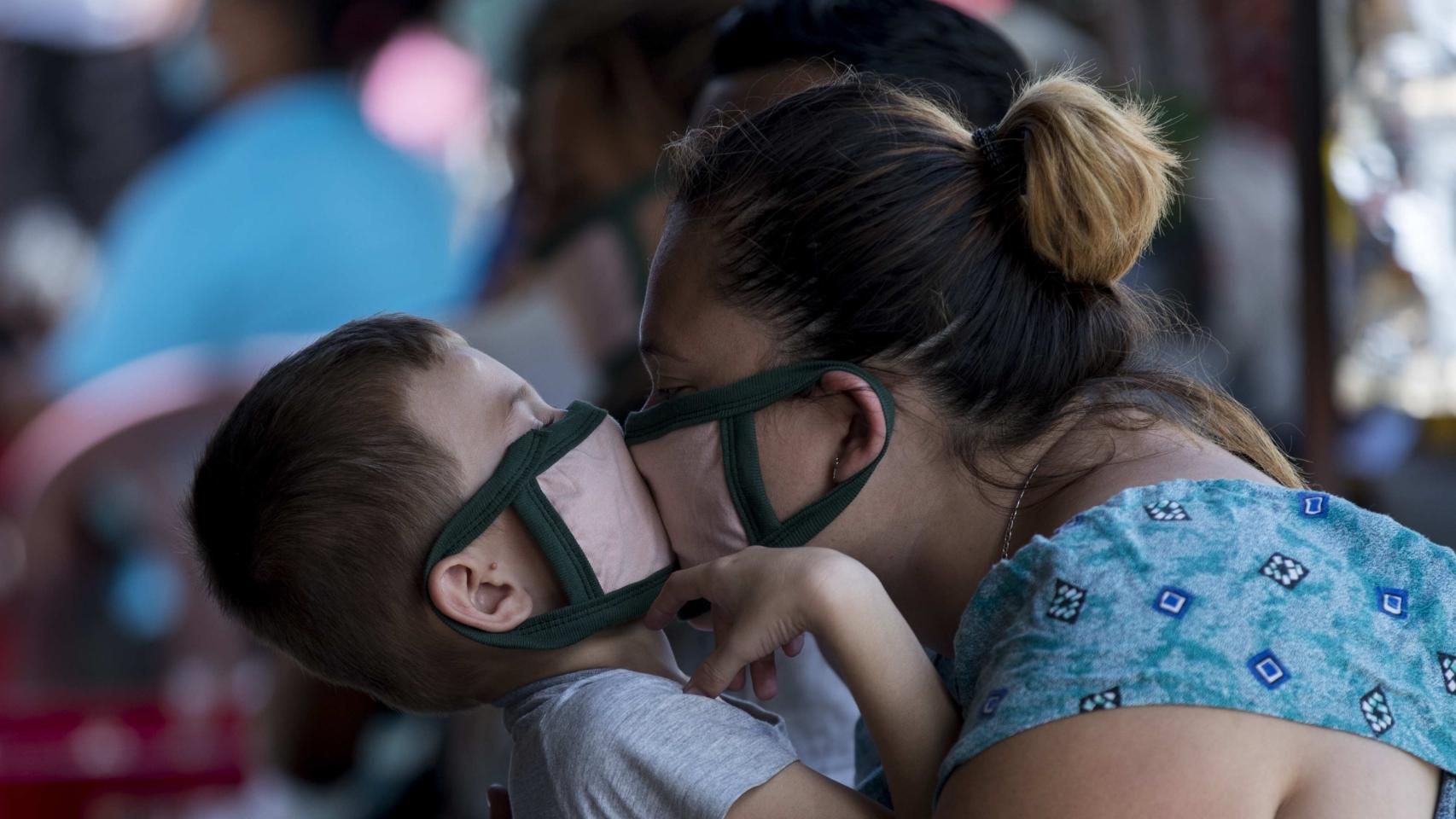 Una mujer con su hijo, portando mascarillas.