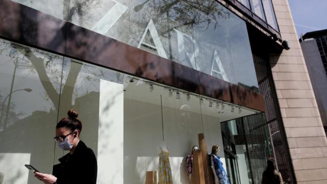 Una mujer con mascarilla pasa junto al escaparate de la tienda Zara de la Calle Princesa de Madrid del grupo Inditex.