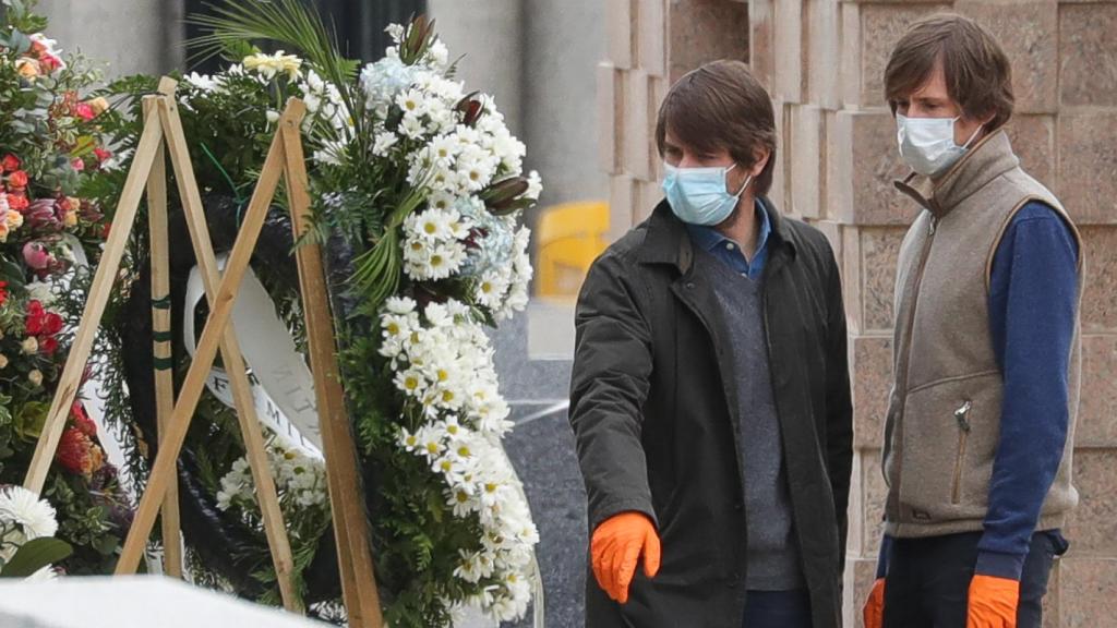 Carlos y Felipe, hijos de Alfonso Cortina, observando las coronas de flores que le han mandado al padre.