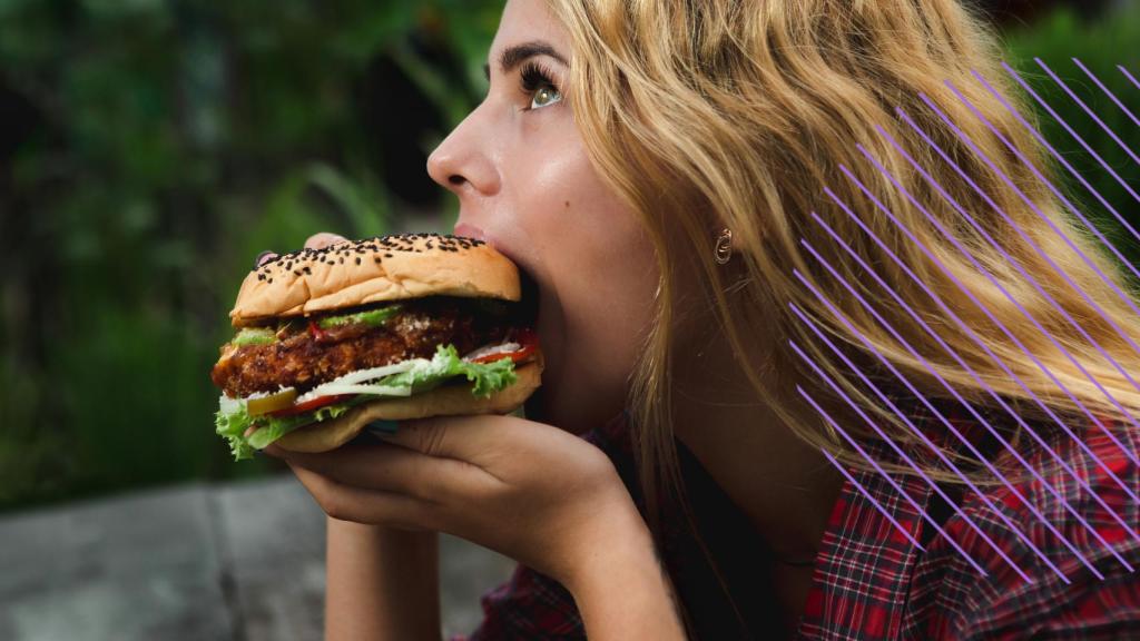 Una mujer comiendo una hamburguesa.