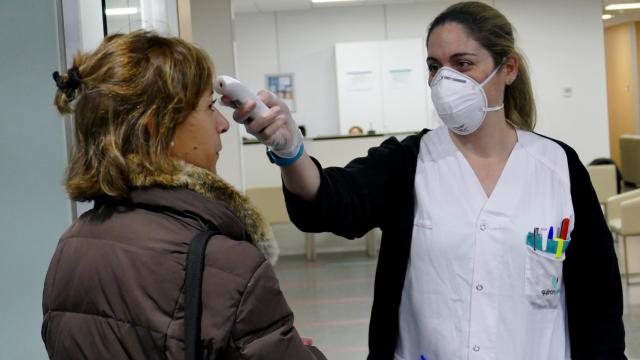 Una sanitaria mide la temperatura de una paciente.