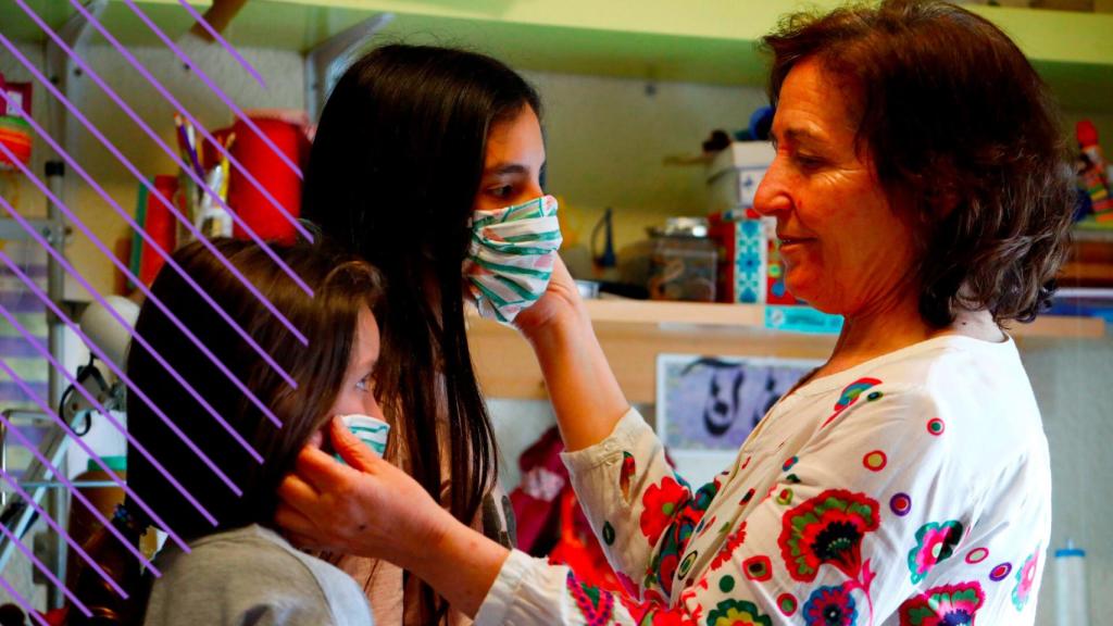 Una mujer prueba dos mascarillas a dos niñas.