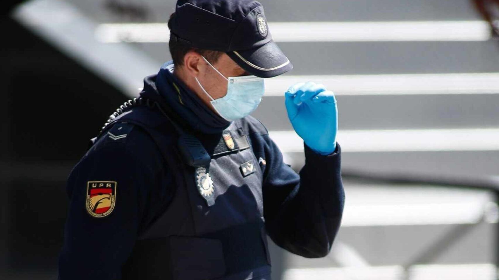 Un agente con el rostro cubierto con una mascarilla.