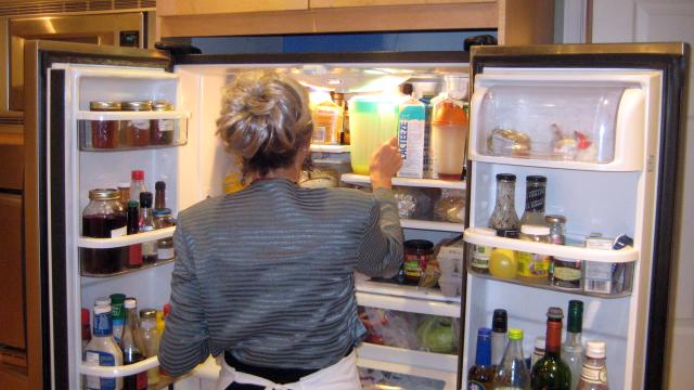 Una mujer mete alimentos en la nevera.