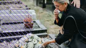 Una mujer dejando flores en una tumba.