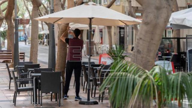 Un camarero prepara la terraza de un bar.