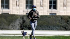 Una mujer corriendo con mascarilla.