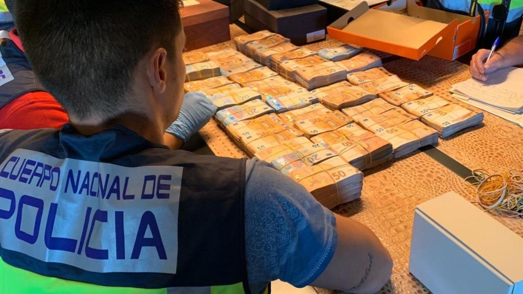 Un policía contando los 1,6 millones que Juan Andrés tenía en una habitación del pánico.