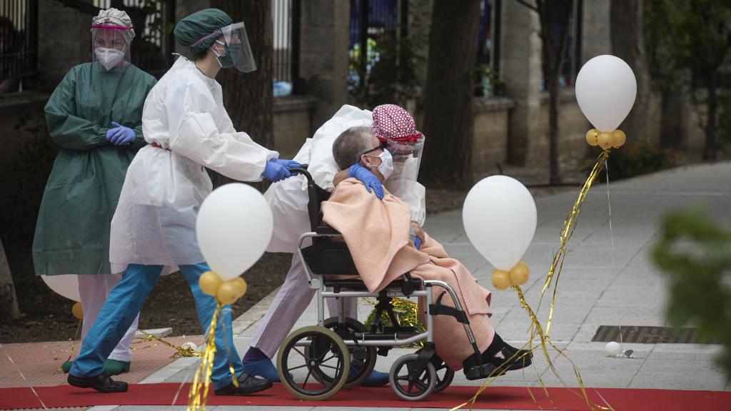 Una anciana en silla de ruedas recibe el cariño del personal sanitario a su llegada a la residencia La Pasionaria.