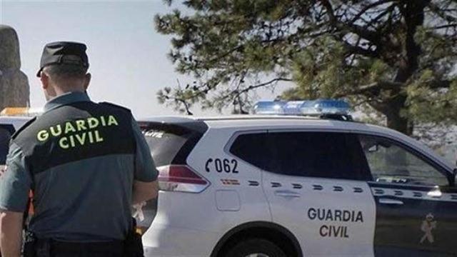 Un agente de la Guardia Civil y su coche uniformado.