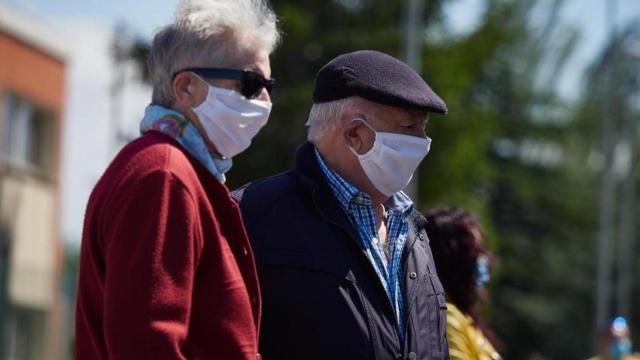 Dos personas mayores llevando mascarilla por la calle.