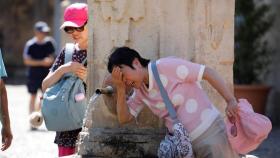 Turistas extranjeros se refrescan en una fuente en Sevilla.