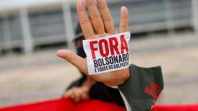 Un manifestante muestra una pegatina en la que se puede leer 'Bolsonaro,  fuera', durante una protesta en Brasilia.