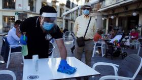 Un camarero desinfecta una mesa en un bar del centro de Málaga.