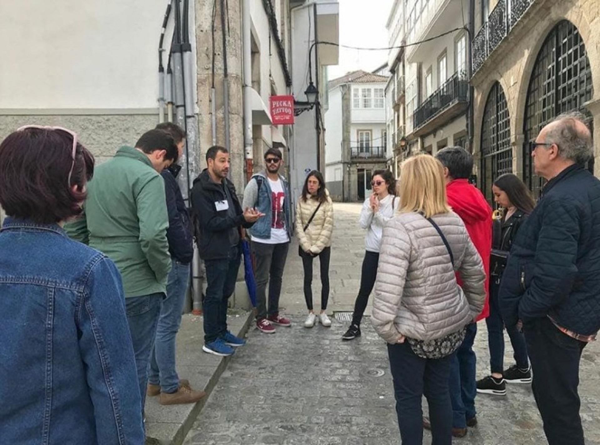 Un guía de Walkin Eating Galicia da información sobre la ciudad a varios turistas.