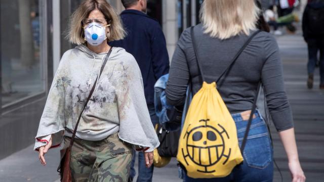 Una mujer paseando con mascarilla por la calle.