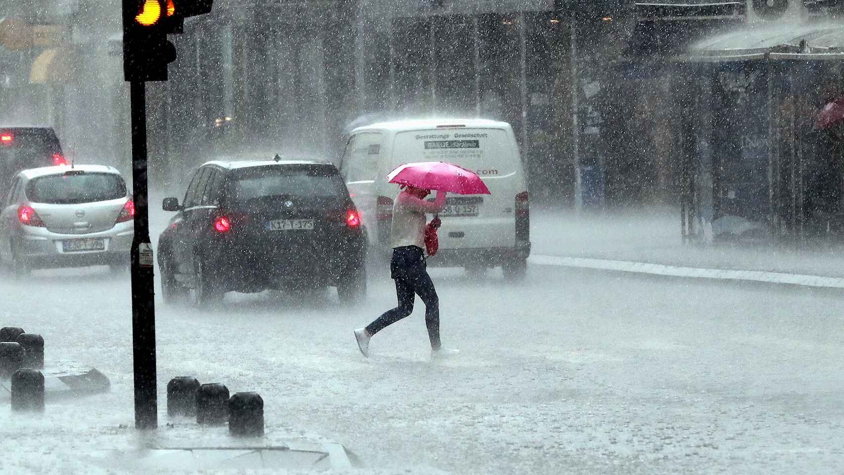 Una mujer cruza la calle bajo una lluvia torrencial. Efe/Epa Fehim Demir