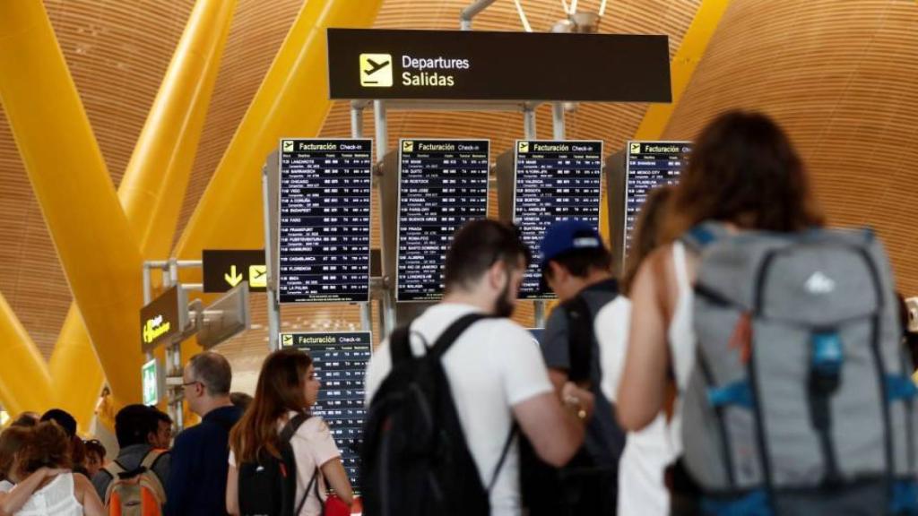 Viajeros mientras esperan en el interior del aeropuerto de Barajas.