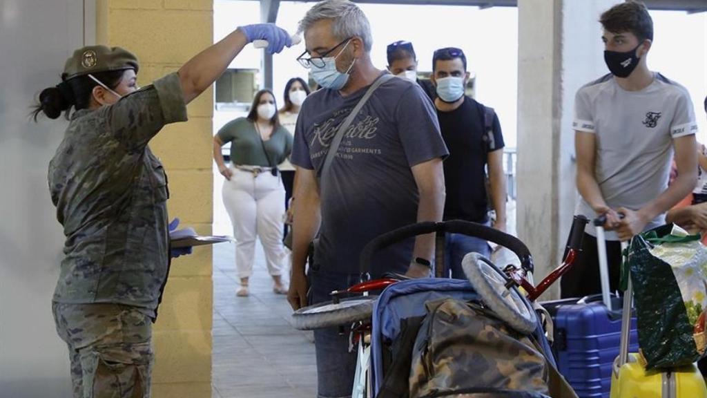 Una enfermera del Ejército toma la temperatura a varios pasajeros.