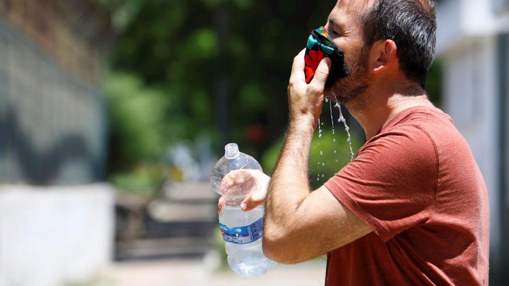 Un joven refrescándose la mascarilla contra el calor en Córdoba. EFE/Salas.