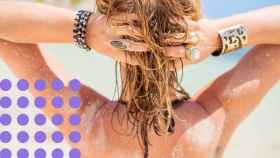 Una mujer tocándose el pelo en la playa.
