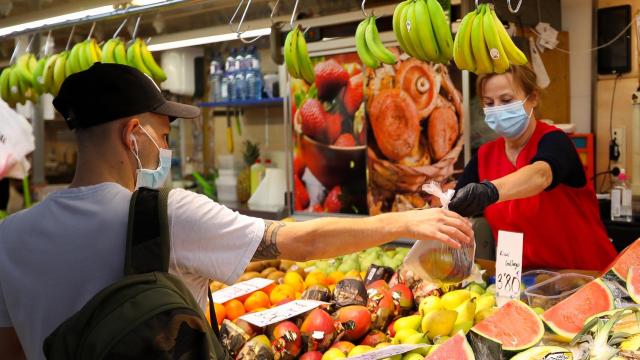 Una trabajadora de una frutería atendiendo a un cliente.