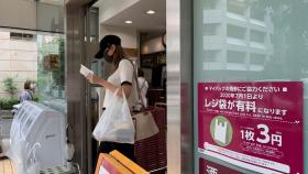 Una mujer abandona un ultramarinos en Tokio, Japón, con una bolsa de plástico desechable, este miércoles.