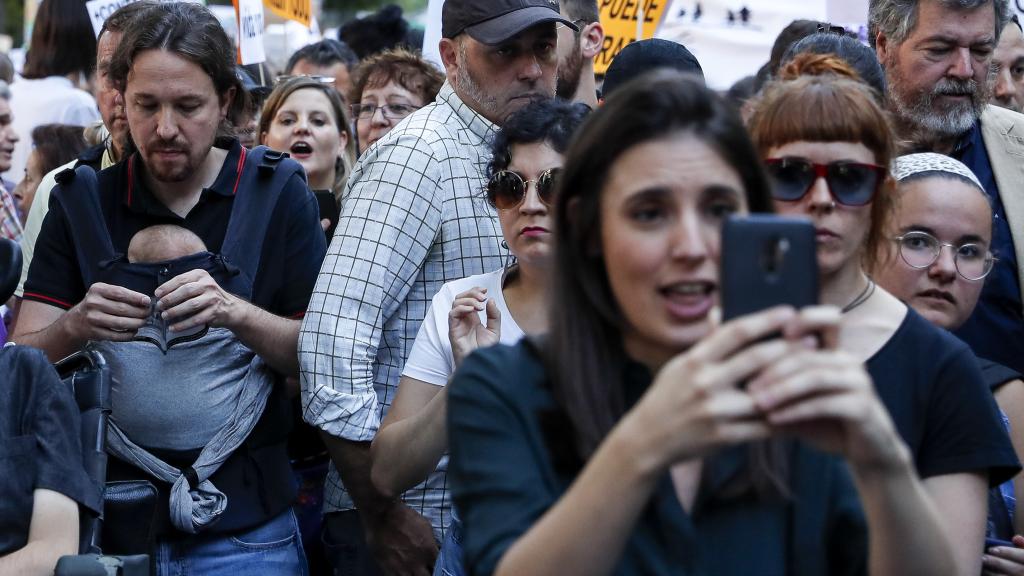 Pablo Iglesias con la pequeña Aitana en su mochila portabebés. En primer plano, Irene Montero con su teléfono móvil.