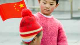 Un niño sostiene una bandera de China en Pekín.