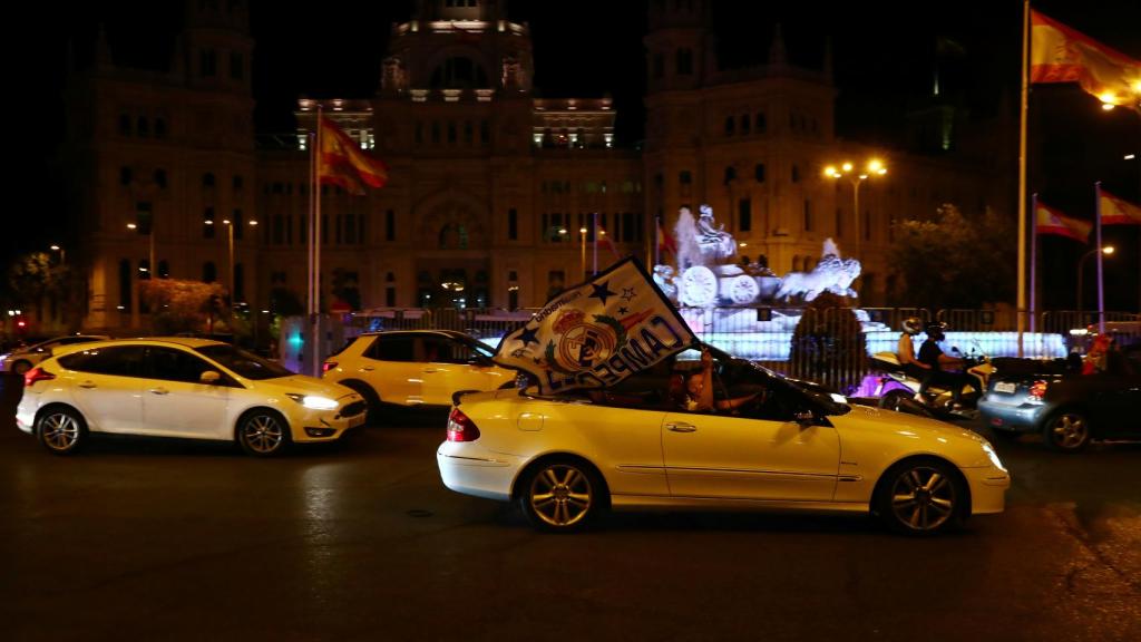 Aficionados del Real Madrid celebran el título de Liga a su paso en coche por La Cibeles