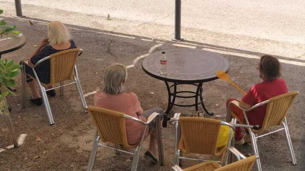 Varias residentes descansan bajo la sombra de un toldo para protegerse del sol del verano.