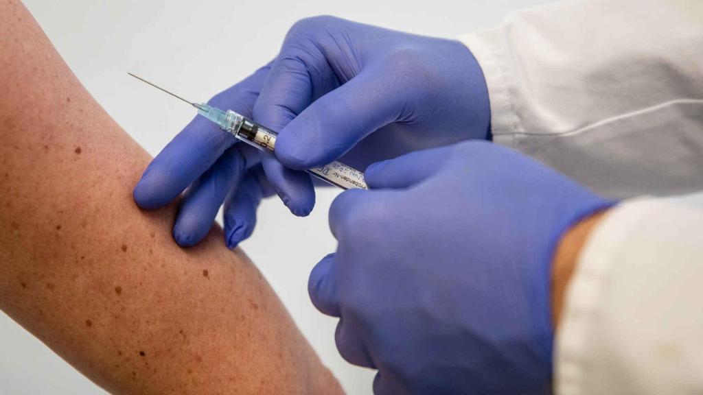 Un sanitario se dispone a inyectar una vacuna.