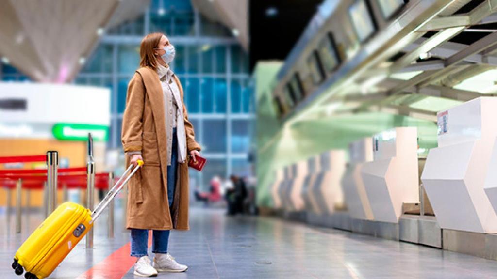 Mujer, con mascarilla, en un aeropuerto