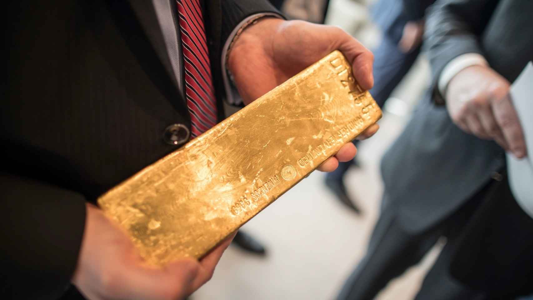 Un hombre sostiene un lingote de oro.