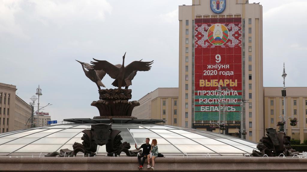 Una pareja posa con un cartel de fondo que reza '9 de agosto 2020 elecciones presidenciales en Bielorrusia'.