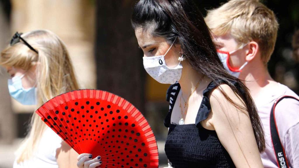 Varias mujeres con mascarillas y abanico caminan esta semana por una calle de Córdoba.