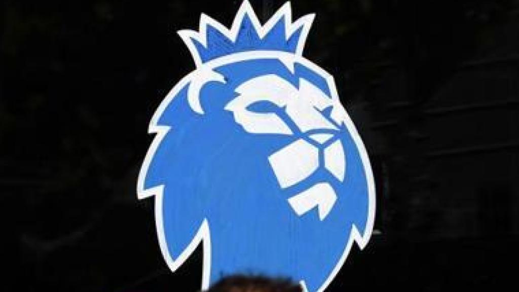 Un hombre con mascarilla frente al logo de la Premier League