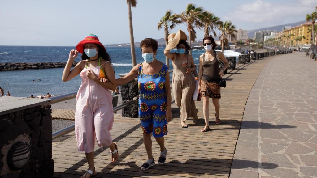 Unos turistas caminan por un paseo cercano a la playa de Las Caletillas, en Tenerife.