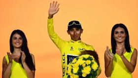 Egan Bernal con el maillot amarillo de la edición de 2019 junto a dos azafatas